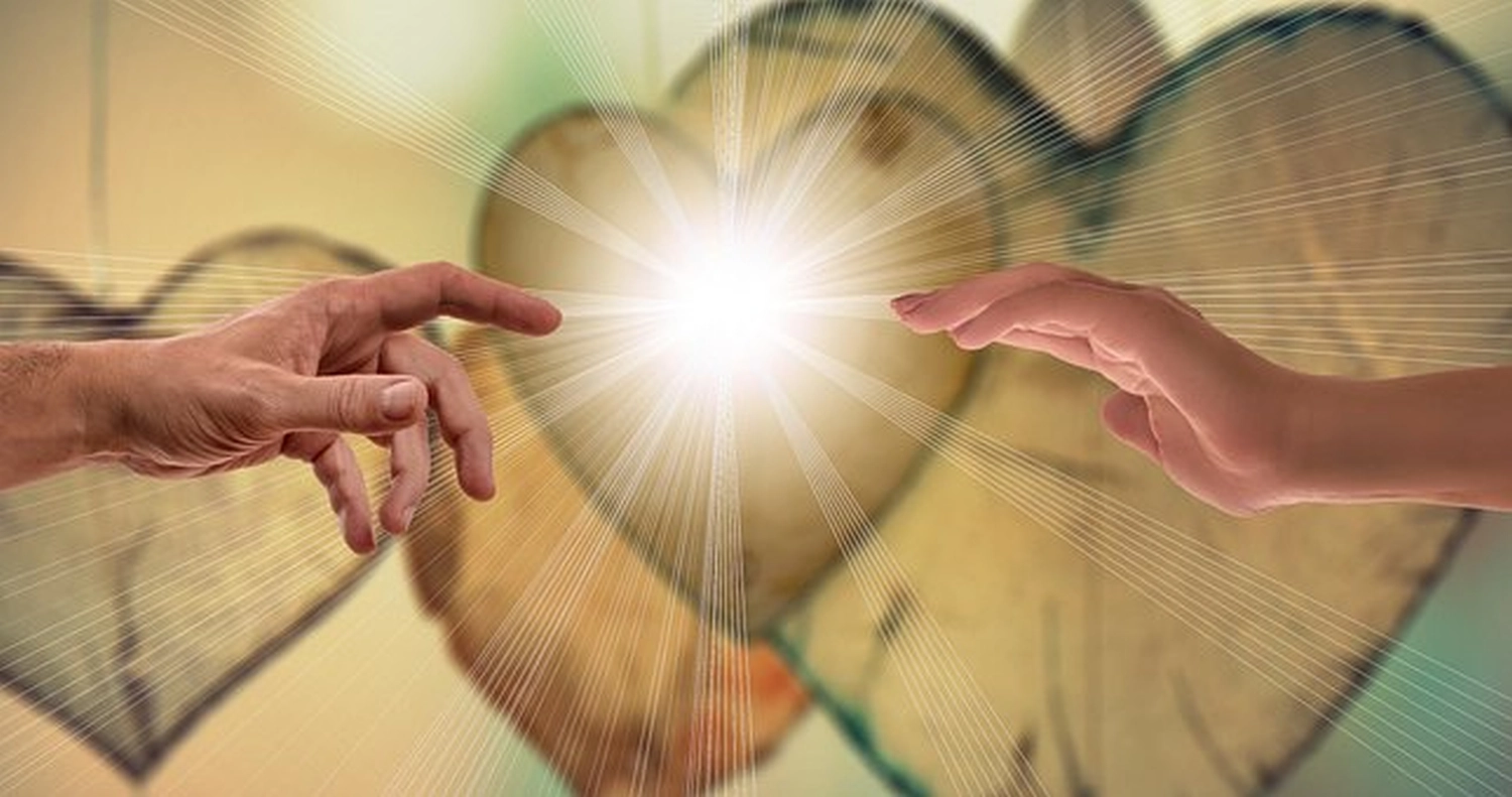 enHealing - Energetischen Praxis, persönlichen Entwicklung und Vitalstoffberatung - Zwei Hände, die sich vor einem Hintergrund aus Holzherzen einander entgegenstrecken, wobei zwischen ihren Fingerspitzen ein heller Lichtblitz aufleuchtet.