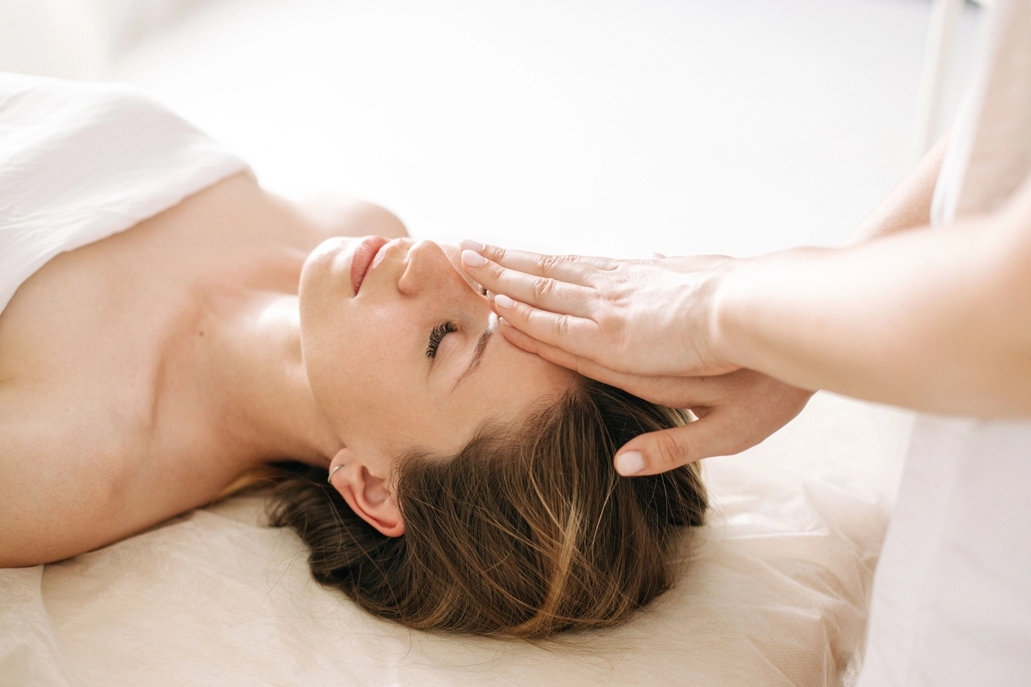 enHealing - Energetischen Praxis, persönlichen Entwicklung und Vitalstoffberatung - Eine wunderschöne junge Frau lässt sich in einem Wellnesszentrum mit Reiki behandeln.